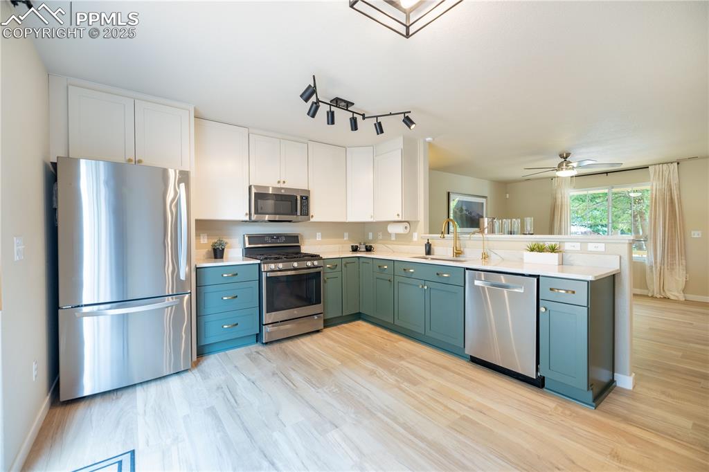 Image 9 of 42: Kitchen featuring appliances with stainless steel finishes, a peninsula, li