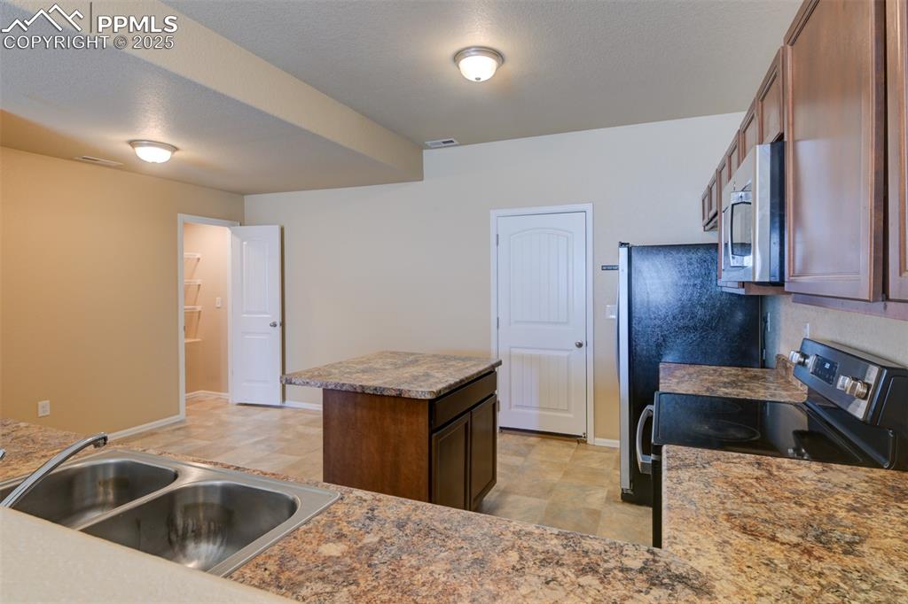 Image 10 of 33: Kitchen featuring range with electric cooktop, a center island, stainless s