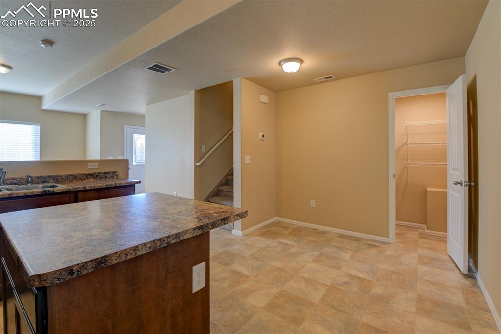 Image 11 of 33: Kitchen with a textured ceiling, a center island, and dark countertops