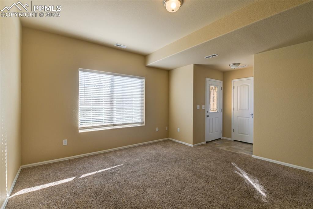 Image 14 of 33: Empty room with healthy amount of natural light and carpet floors