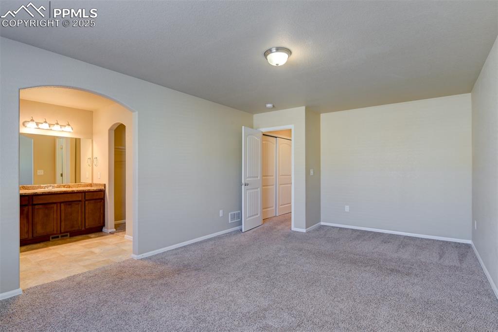 Image 20 of 33: Unfurnished bedroom featuring light colored carpet, a closet, arched walkwa