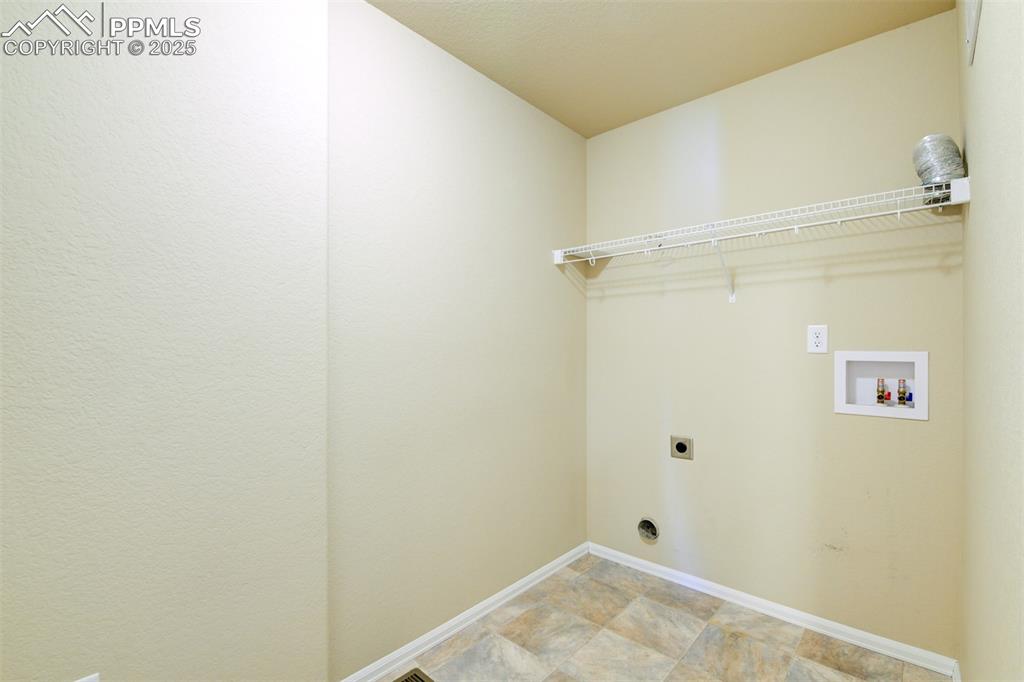 Image 28 of 33: Laundry room with hookup for an electric dryer, washer hookup, and stone fi