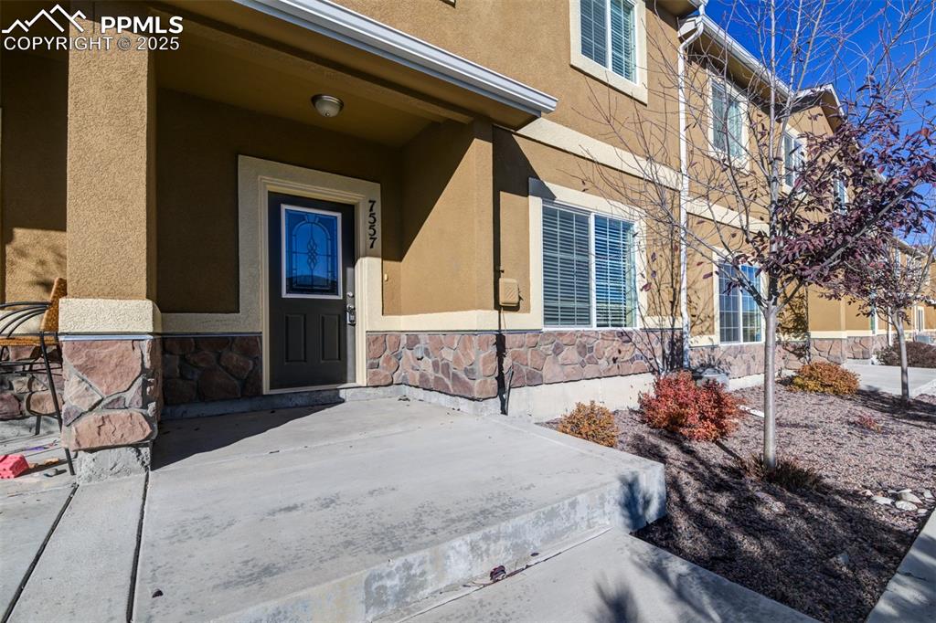 Image 3 of 33: Doorway to property featuring stucco siding and stone siding