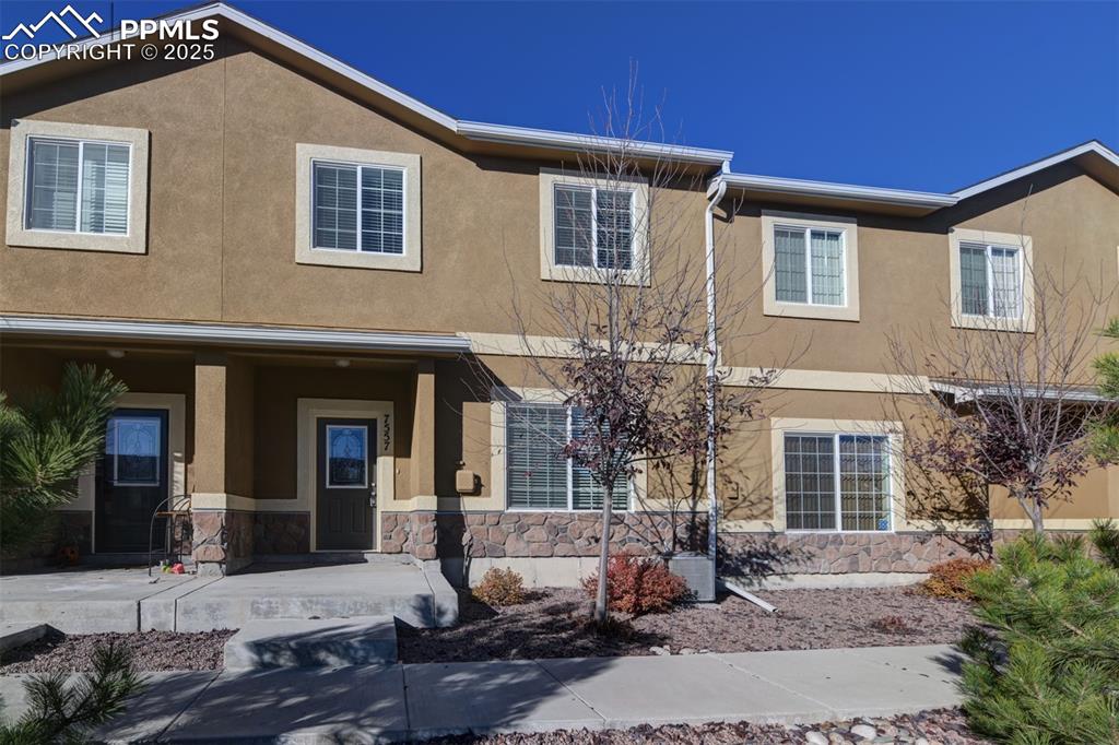 Image 33 of 33: View of front of home with a porch, stucco siding, and stone siding