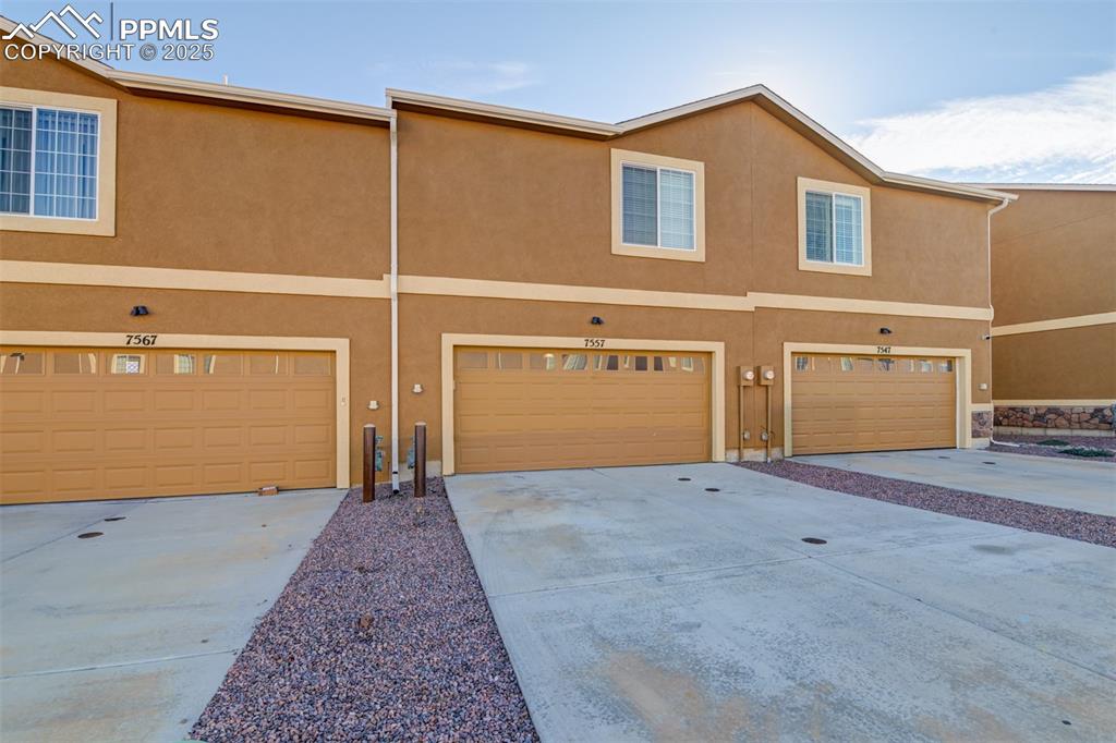 Image 7 of 33: Traditional-style house featuring stucco siding, concrete driveway, and a g