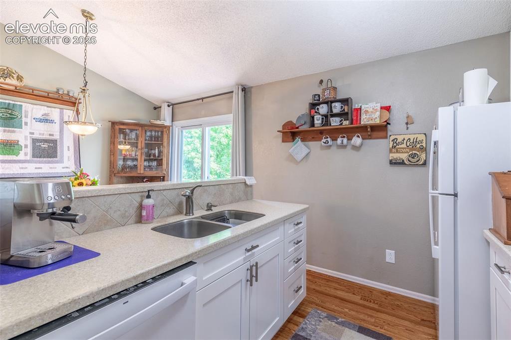 Image 11 of 24: Kitchen featuring white cabinetry, light-toned countertops, and a double-ba