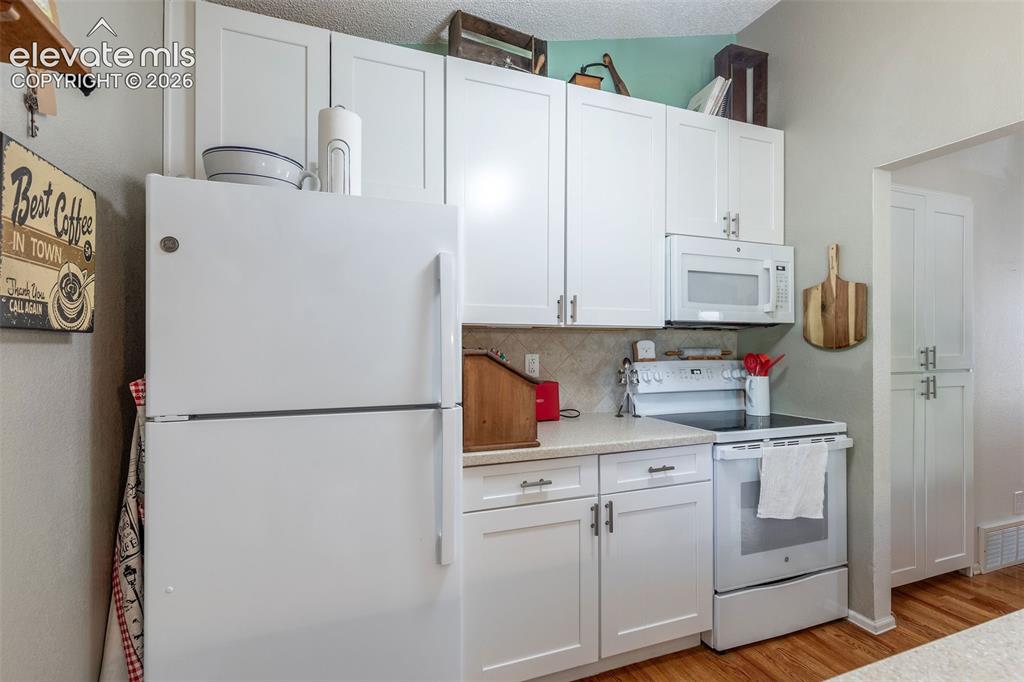 Image 12 of 24: Kitchen featuring white shaker-style cabinetry, a white refrigerator, and a