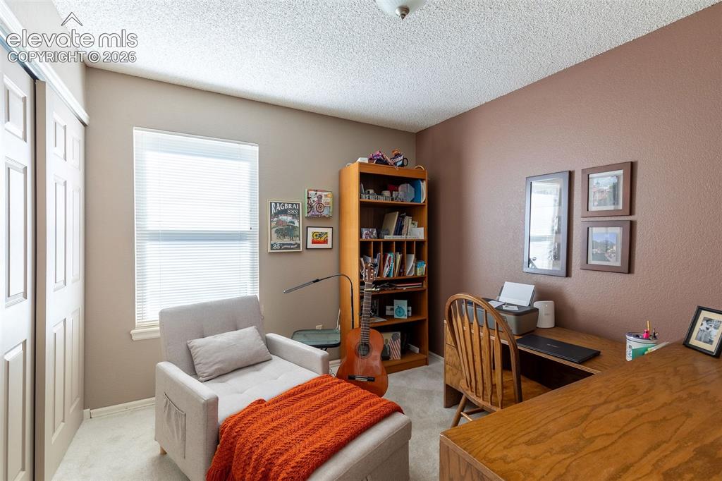 Image 14 of 24: Neutral-toned room featuring a large window with blinds and textured walls