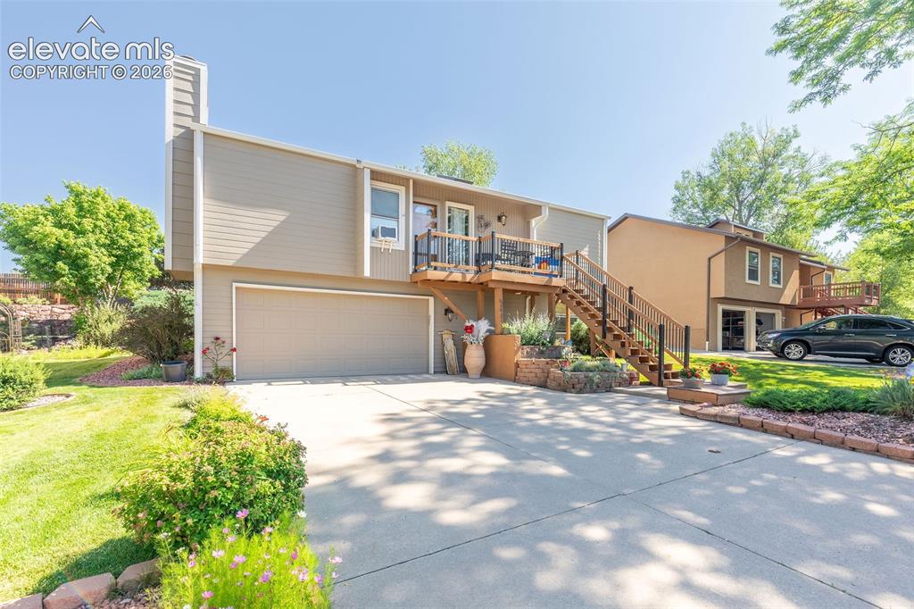 Image 2 of 24: Split-level residence featuring a multi-level deck with dark railings, a tw