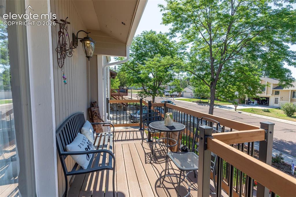 Image 5 of 24: Exterior balcony with wood-finish decking, black railings, and wood-toned t