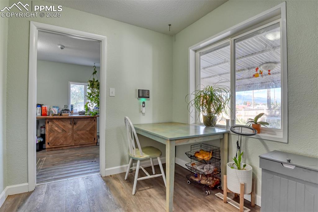 Image 10 of 45: Dining space with a textured wall, wood finished floors, and a textured cei