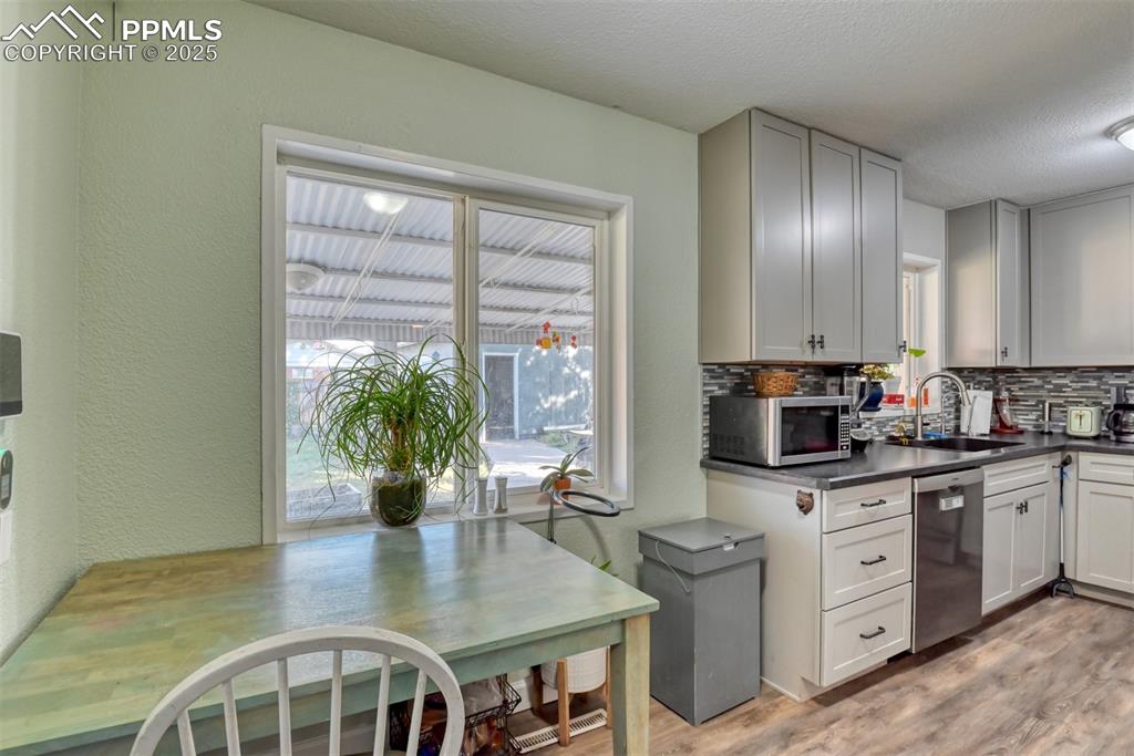 Image 11 of 45: Kitchen with a textured wall, dark countertops, light wood-style flooring,