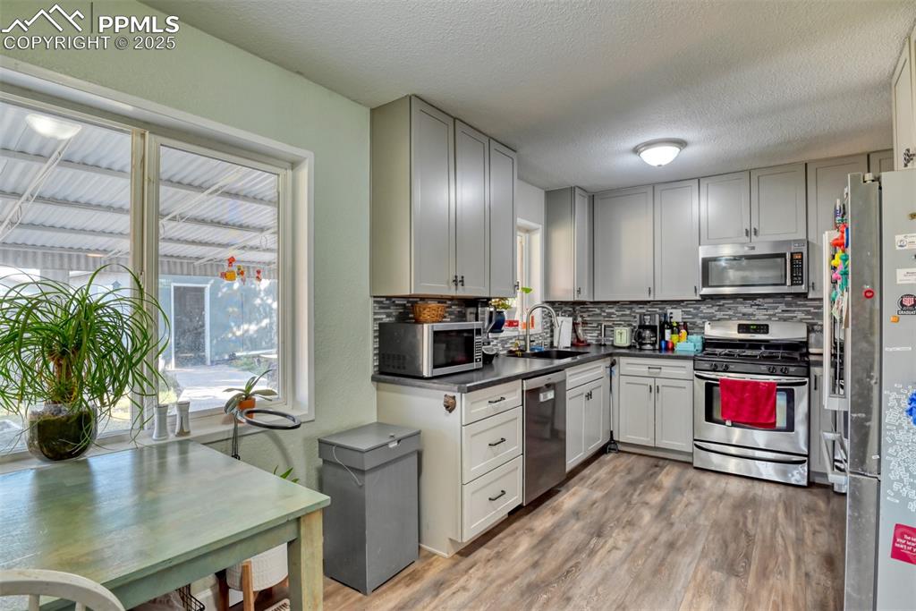 Image 12 of 45: Kitchen with appliances with stainless steel finishes, dark countertops, ta