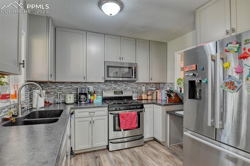 Image 13 of 45: Kitchen with stainless steel appliances, tasteful backsplash, a textured ce