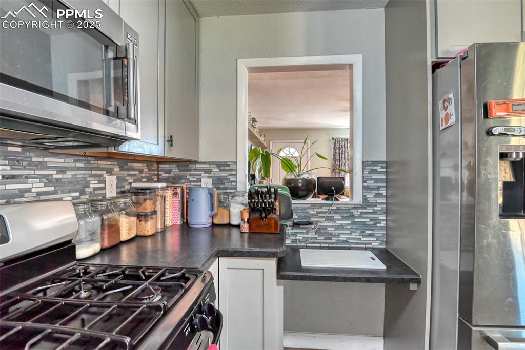 Image 15 of 45: Kitchen with appliances with stainless steel finishes, decorative backsplas