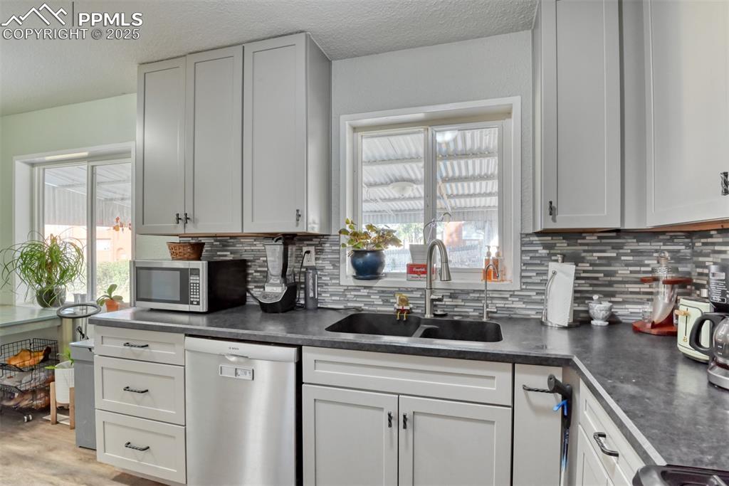 Image 16 of 45: Kitchen with dark countertops, stainless steel appliances, decorative backs