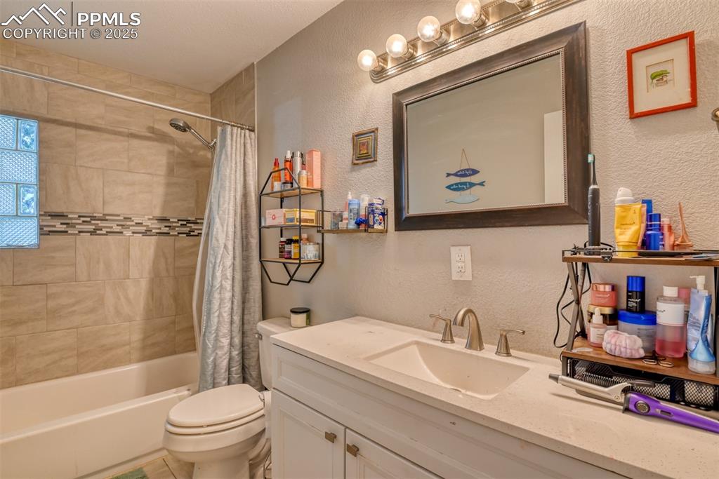 Image 18 of 45: Bathroom featuring a textured wall, shower / bath combo with shower curtain