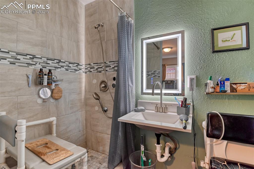 Image 19 of 45: Bathroom featuring a textured wall and a stall shower