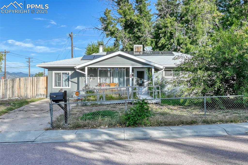Image 2 of 45: Bungalow-style home with roof mounted solar panels, a fenced front yard, an