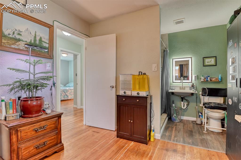 Image 26 of 45: Bathroom with a shower stall, light wood-type flooring, and a textured wall