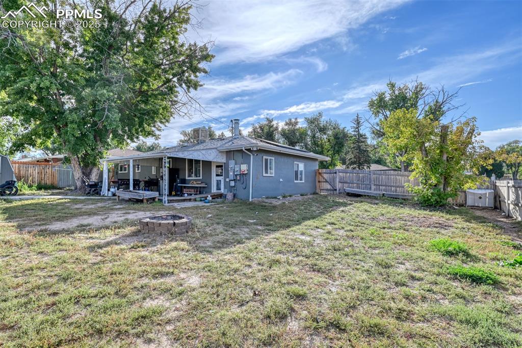 Image 40 of 45: Rear view of property with a fenced backyard, a fire pit, and stucco siding