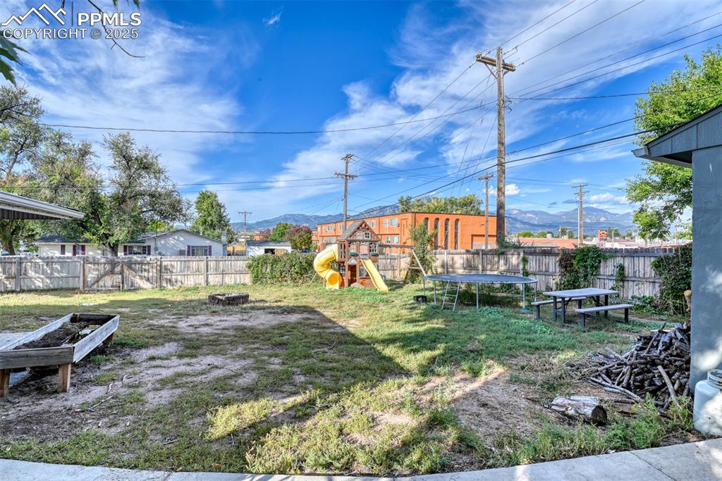 Image 41 of 45: Fenced backyard with a trampoline, a playground, a mountain view, and an ou