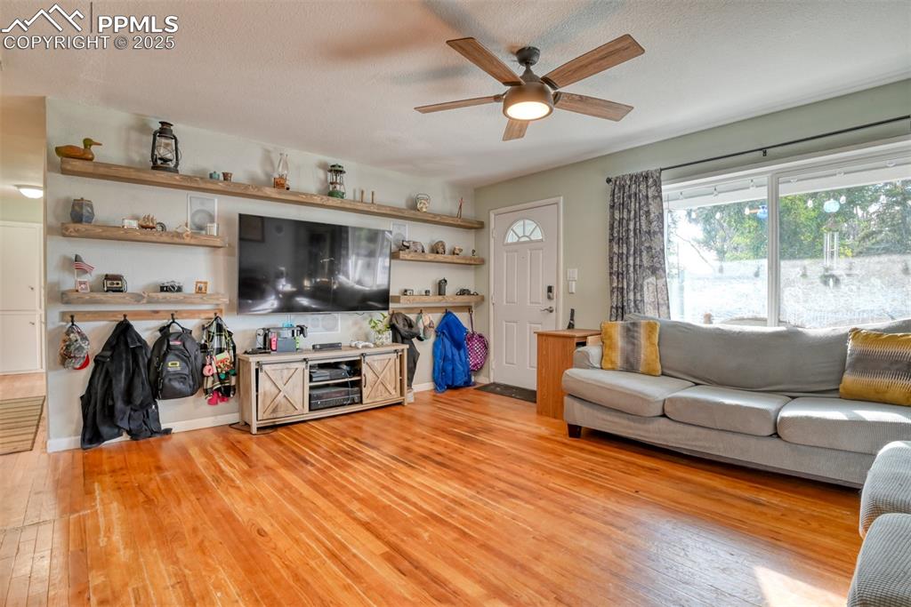 Image 7 of 45: Living room featuring light wood-type flooring, a ceiling fan, and a textur