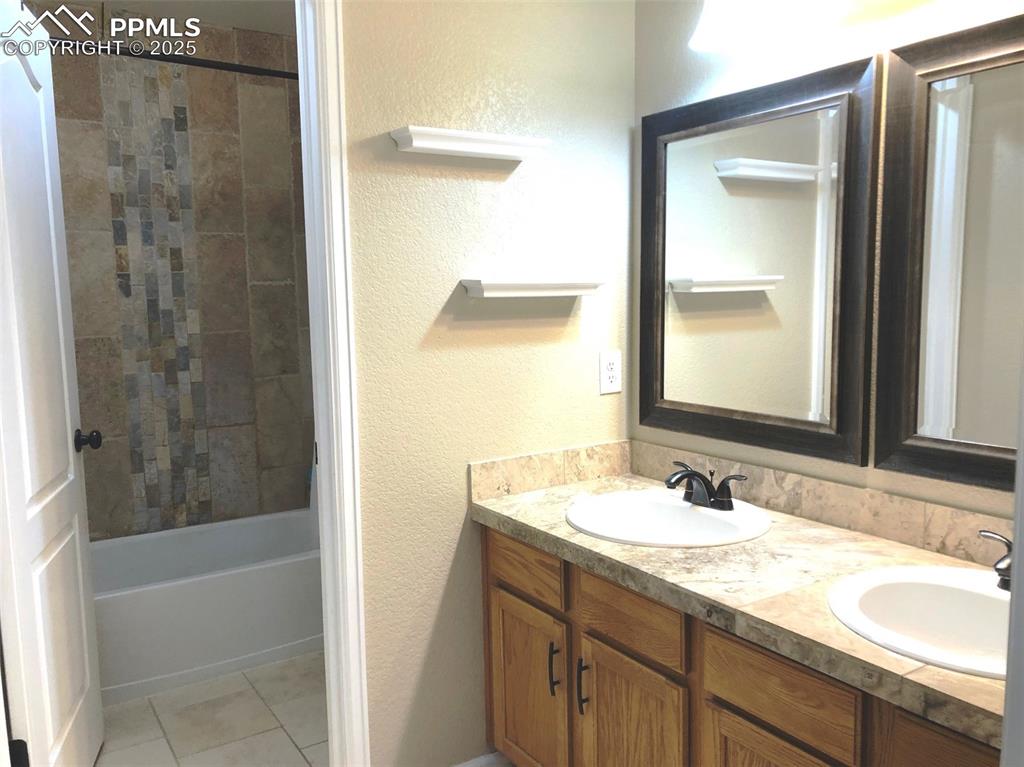 Image 16 of 26: Primary Bath featuring a double vanity, tile patterned floors, and washtub 