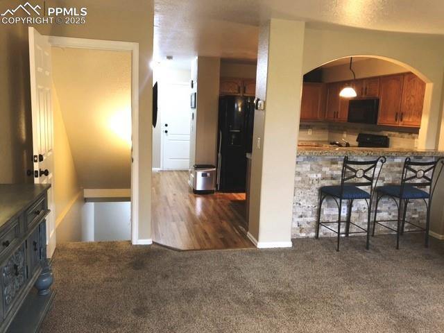 Image 18 of 26: View to down stairs with arched  kitchen bar