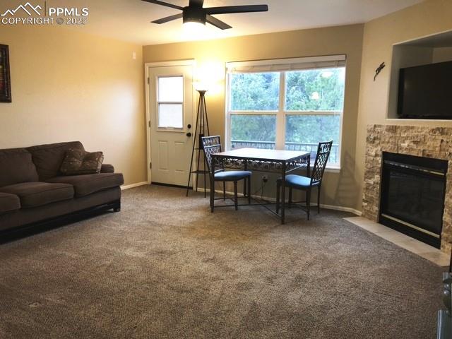 Image 7 of 26: Carpeted living area with a ceiling fan and a stone fireplace