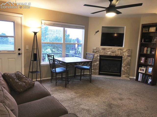 Image 8 of 26: Carpeted dining room featuring a stone fireplace and ceiling fan