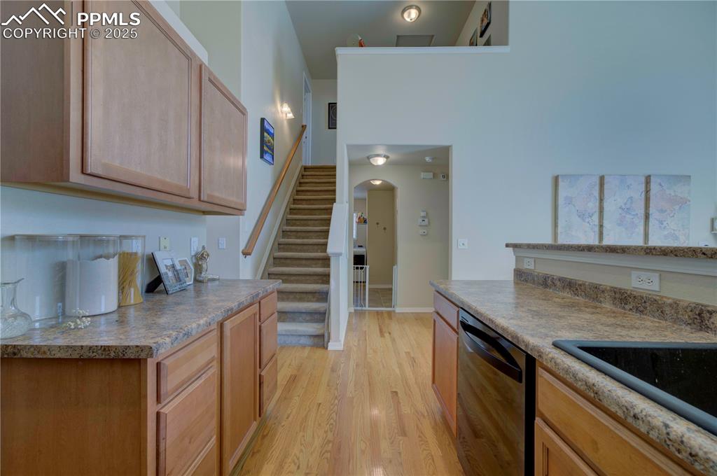 Image 10 of 49: Kitchen featuring black dishwasher, arched walkways, light wood-style floor