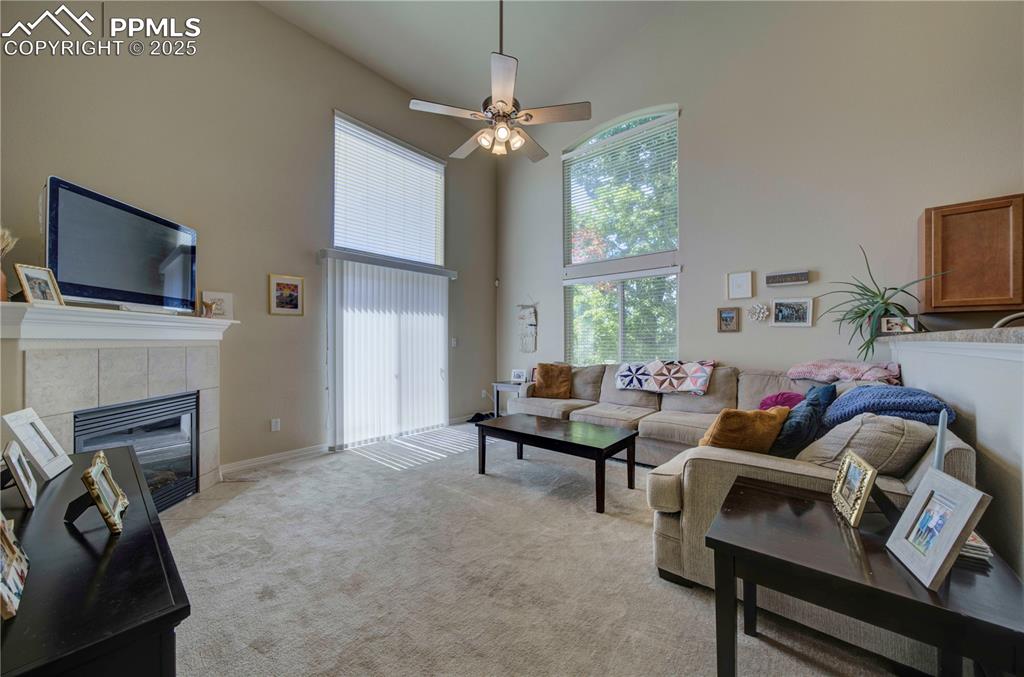 Image 13 of 49: Living room featuring a high ceiling, a fireplace, light carpet, and a ceil