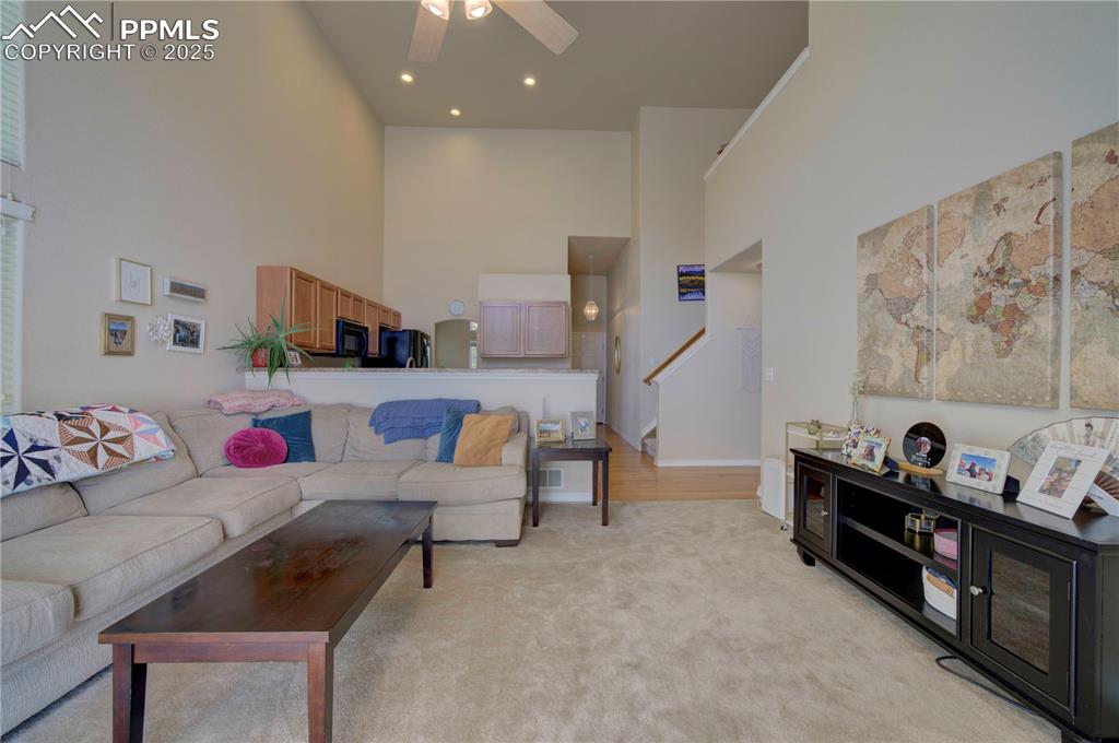 Image 16 of 49: Living room with a high ceiling, a ceiling fan, light wood-style flooring,