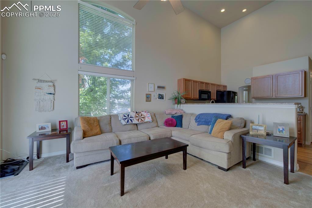 Image 17 of 49: Living area with a towering ceiling, light carpet, recessed lighting, and c