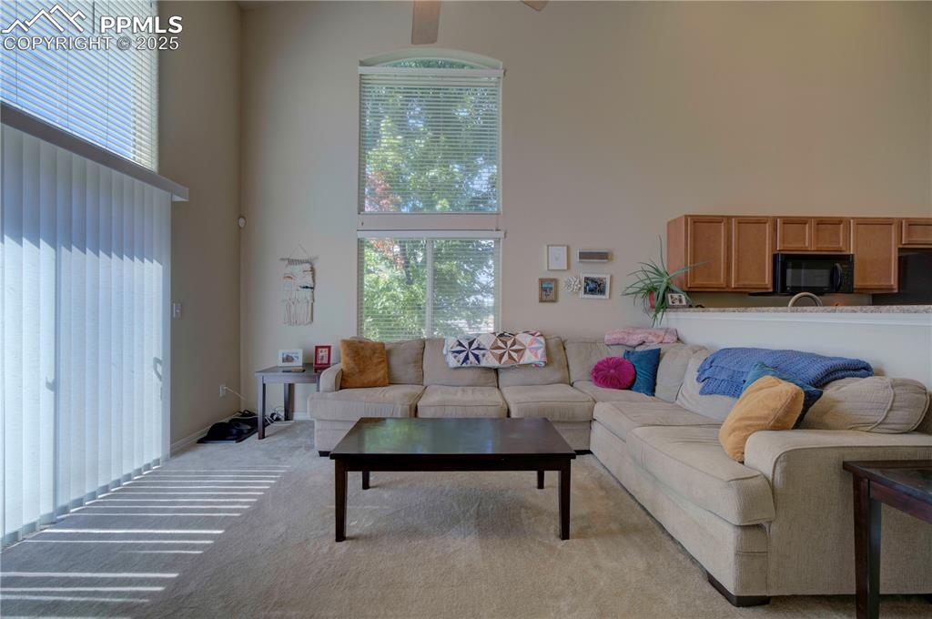 Image 18 of 49: Living area featuring a high ceiling, plenty of natural light, carpet, and