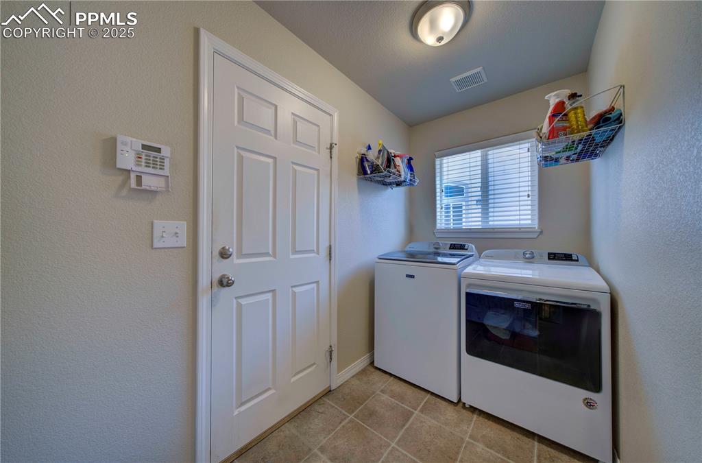 Image 23 of 49: Laundry area with a textured wall, washing machine and clothes dryer, and l