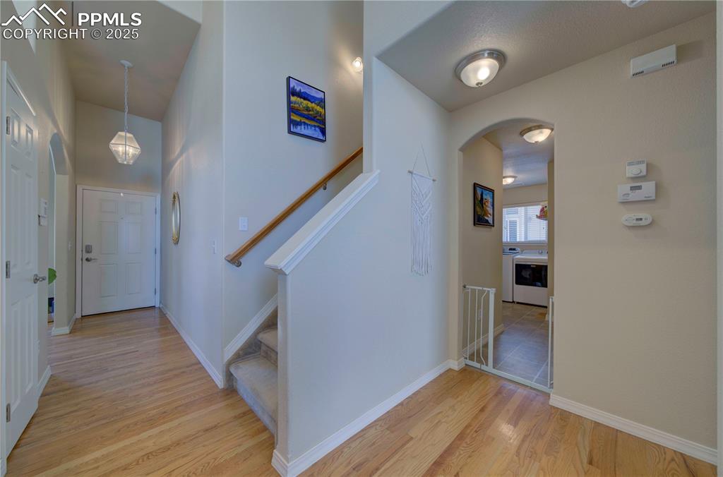 Image 26 of 49: Hallway featuring arched walkways, stairway, light wood-style floors, and w