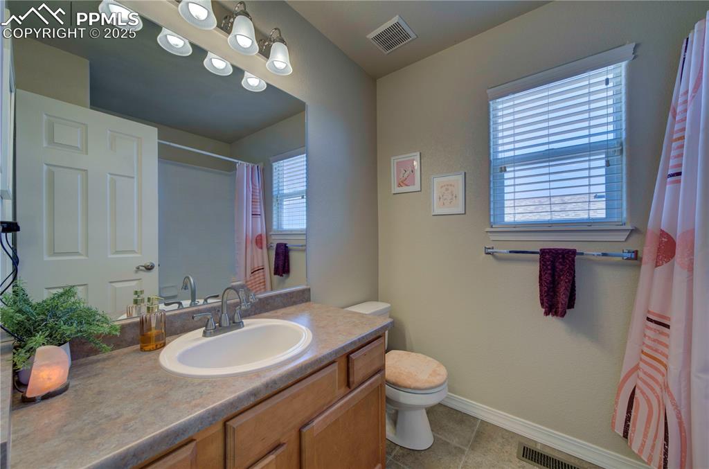 Image 35 of 49: Full bath with vanity, light tile patterned floors, and curtained shower