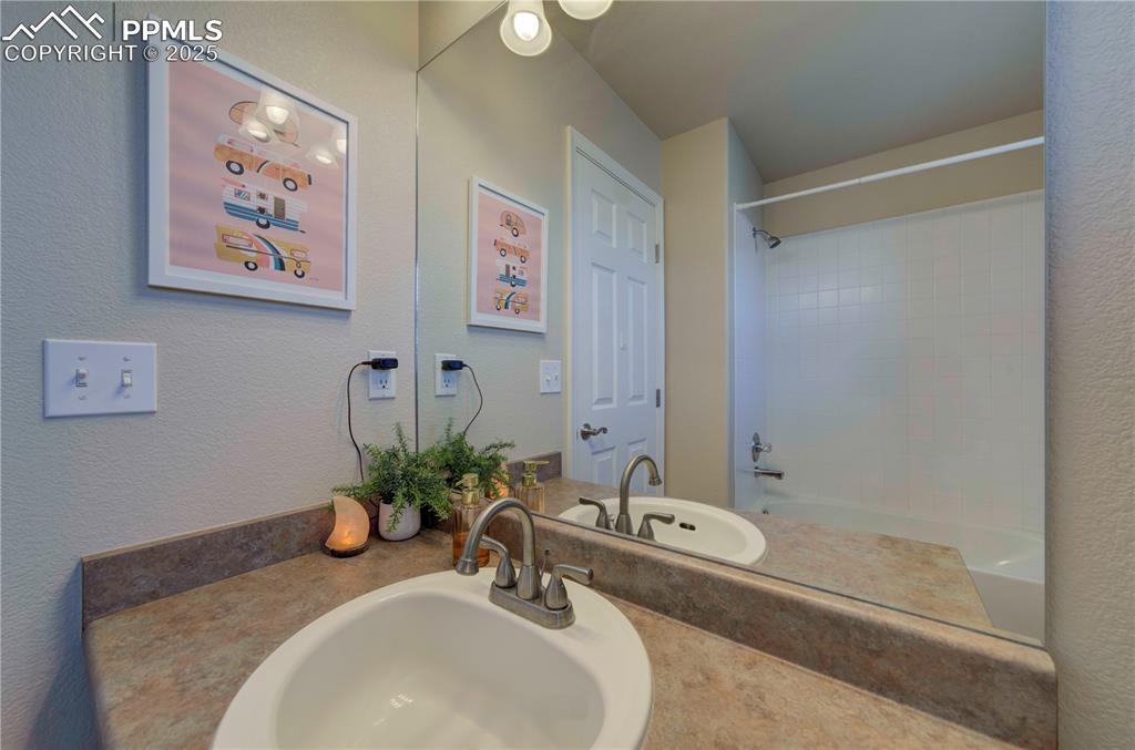 Image 36 of 49: Full bath with bathtub / shower combination, a textured wall, and vanity