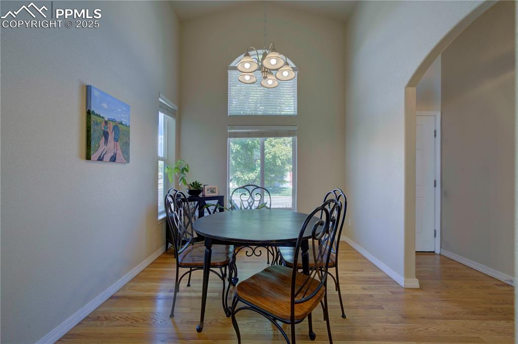 Image 5 of 49: Dining space featuring a towering ceiling, light wood finished floors, arch