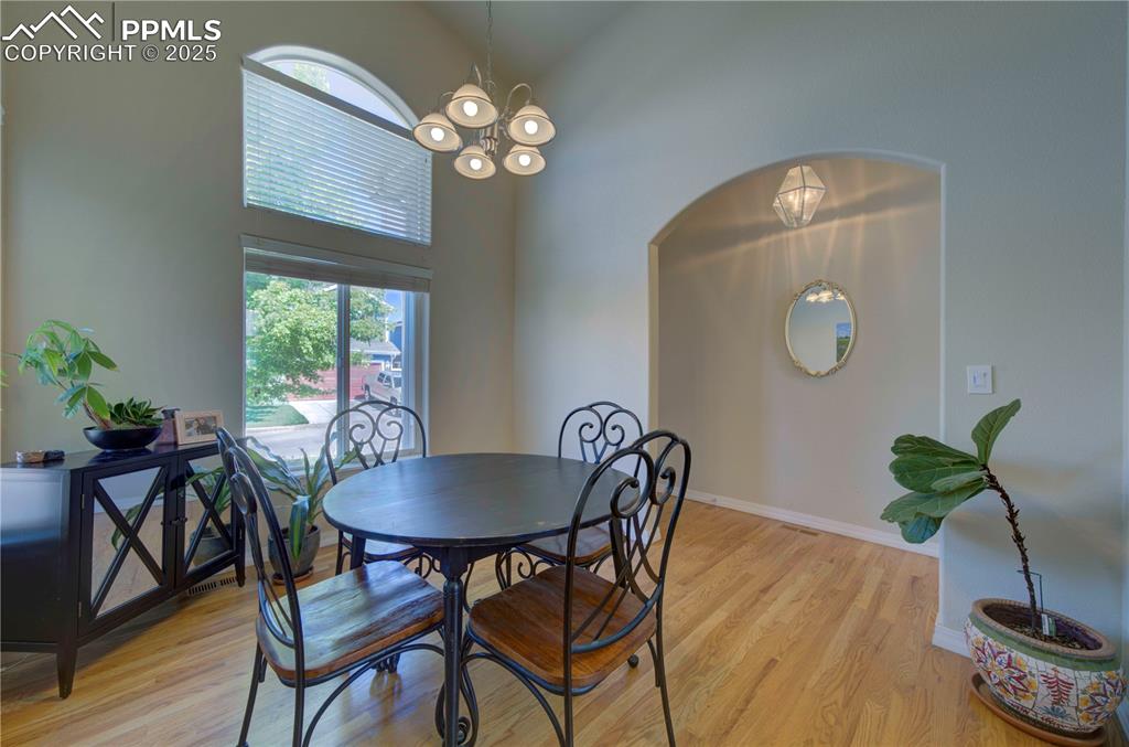 Image 6 of 49: Dining space with a towering ceiling, wood finished floors, arched walkways