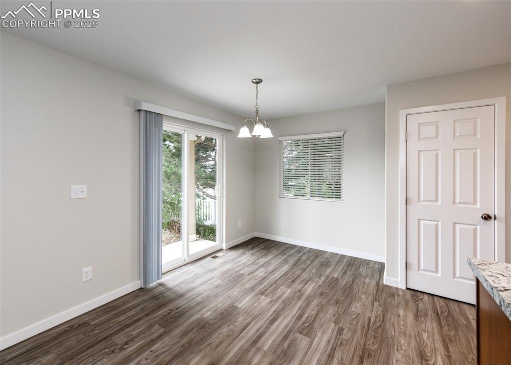 Image 10 of 45: Unfurnished dining area featuring dark wood-style flooring and a chandelier