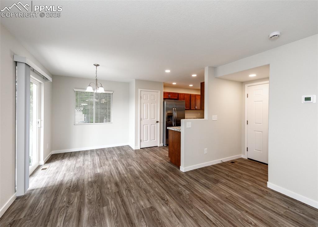 Image 3 of 45: Unfurnished living room with a chandelier, dark wood-style flooring, and re
