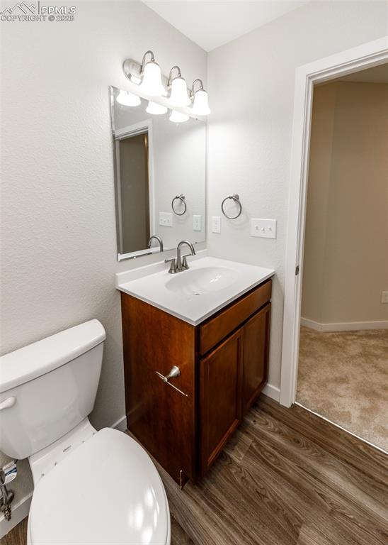 Image 38 of 45: Half bathroom featuring vanity and dark wood finished floors