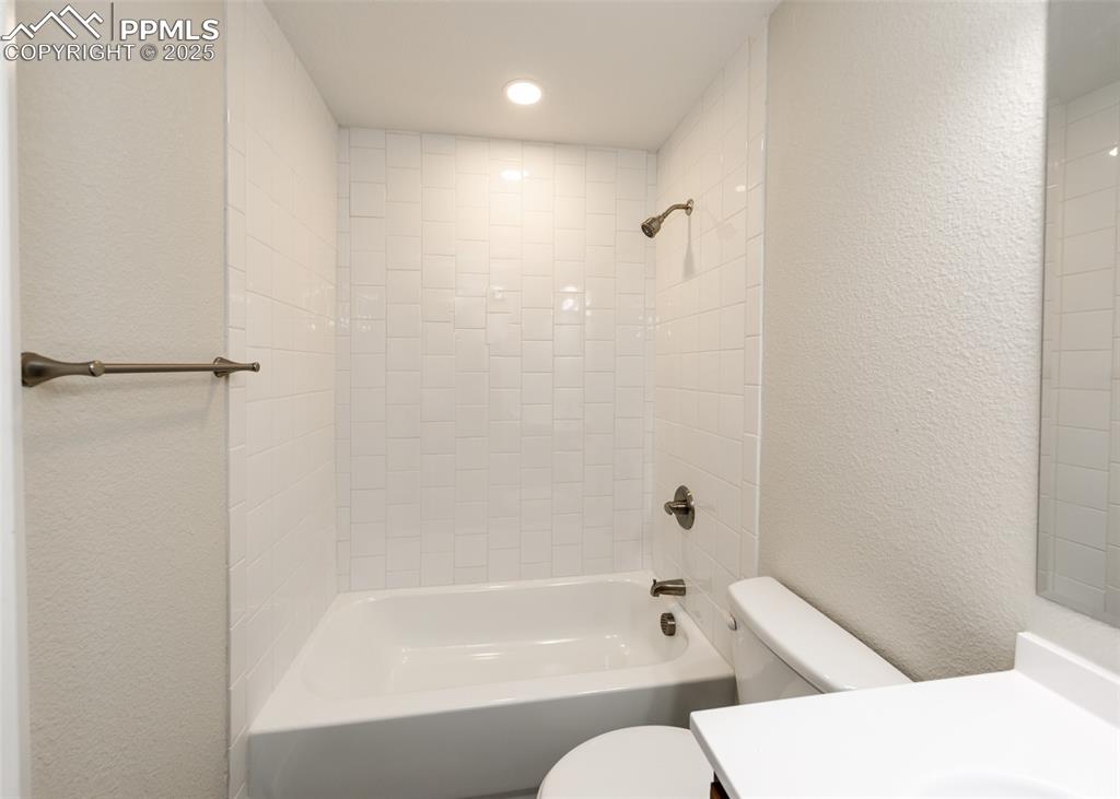 Image 40 of 45: Full bathroom featuring a textured wall, vanity, and  shower combination