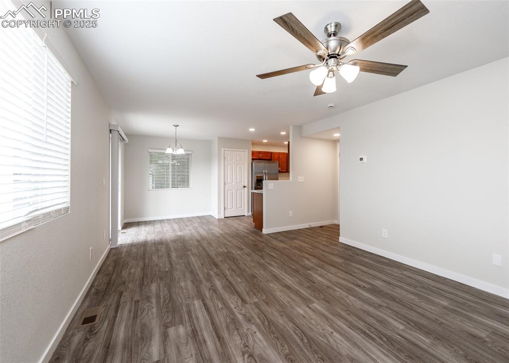 Image 8 of 45: Unfurnished living room with dark wood finished floors, a chandelier, a cei
