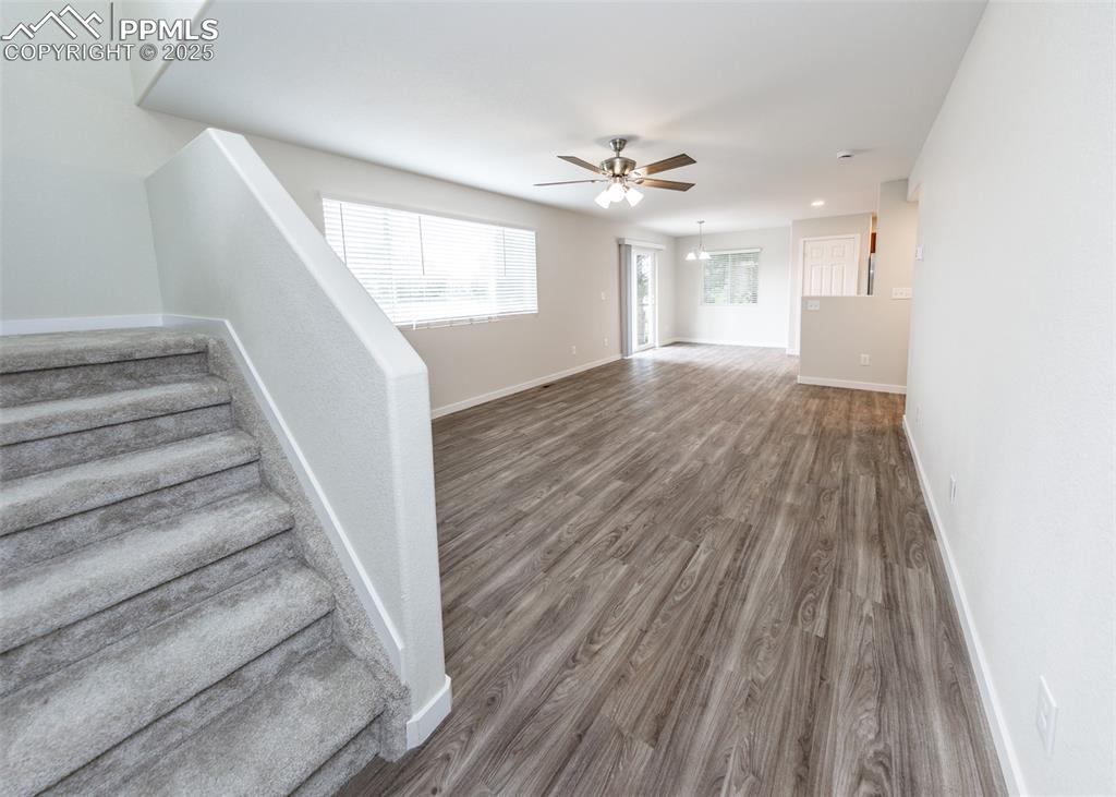 Image 9 of 45: Unfurnished living room with wood finished floors, stairway, and a ceiling 