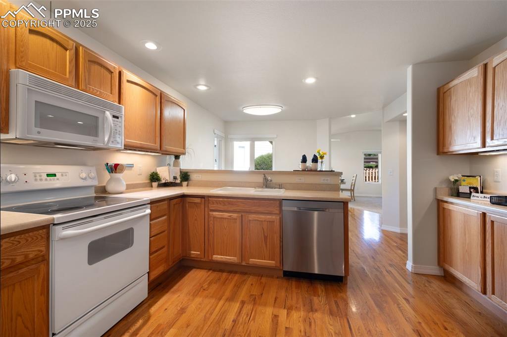 Image 10 of 38: Kitchen with white appliances, a peninsula, light wood finished floors, rec