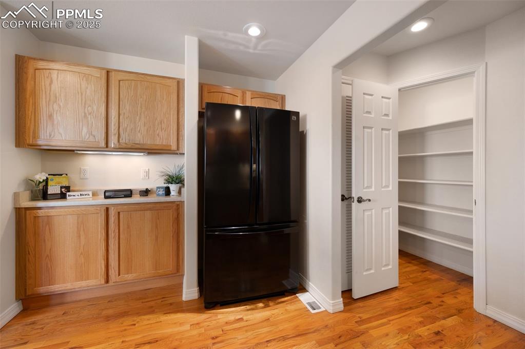 Image 11 of 38: Kitchen with freestanding refrigerator, light countertops, light wood-style